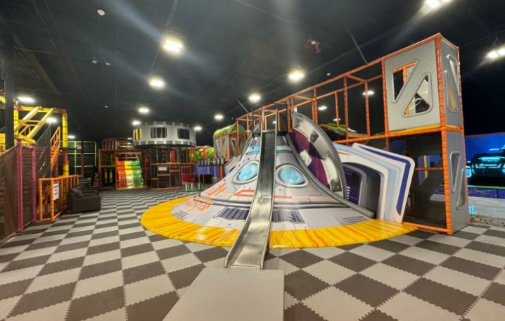 Huge indoor playground with a spaceship slide and multi-level play towers with slides at Nova Adventure Park